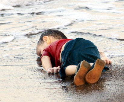 A 3 year old boy who drowned in a failed attempt to sail to the Greek island of Kos, lies on the shore in the Turkish coastal town of Bodrum, Turkey.